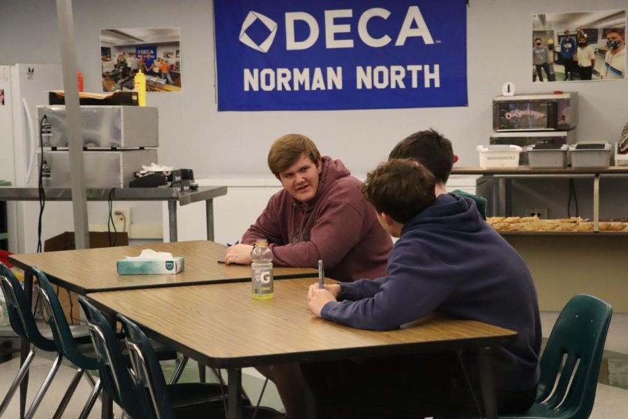 DECA students sit in the DECA room and talk. Fresh made cookies are ready in the background.
