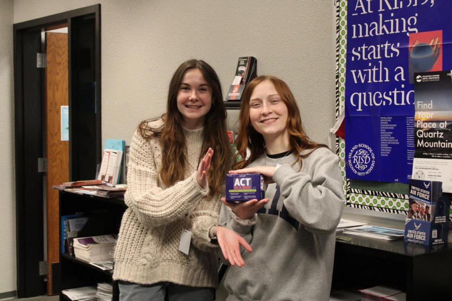 Two students pose by the counselors offices with some of the college preparation materials available.