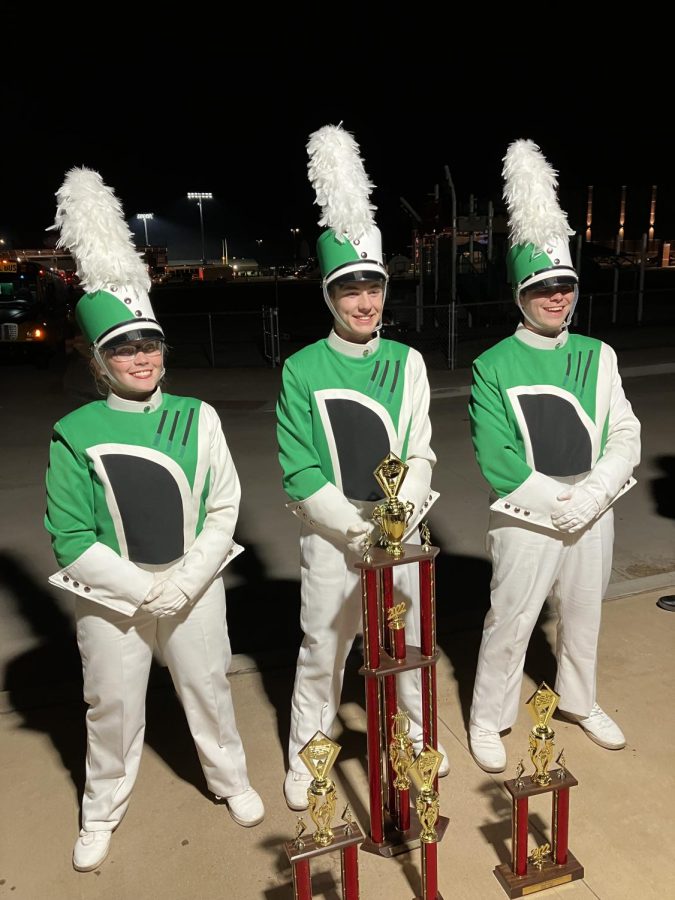 The 2022-2023 Drum Majors standing behind trophies won at Elgin Marching Contest.