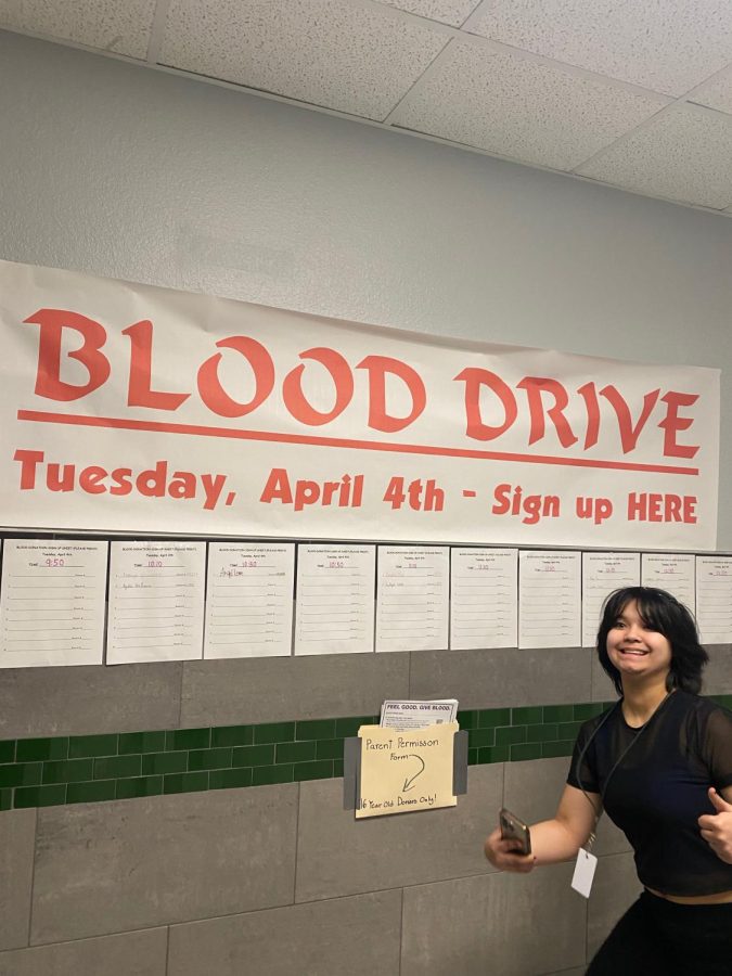 Trinket Standing In front of Blood Drive Poster