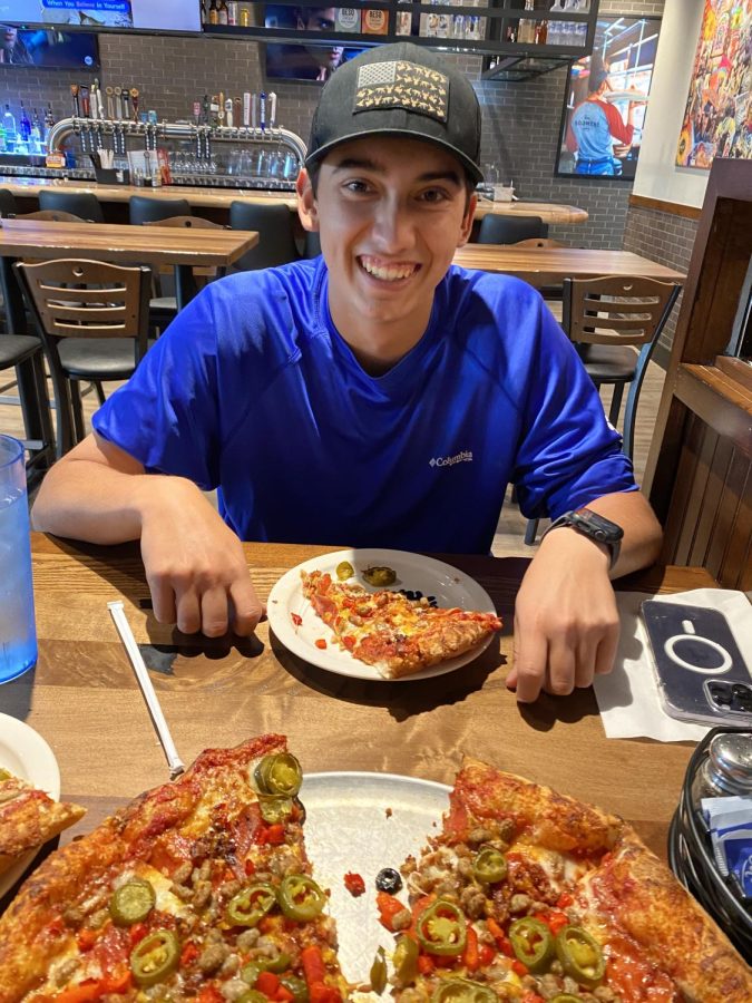 A Norman North student poses with a slice of pizza at Hideaway Pizza.